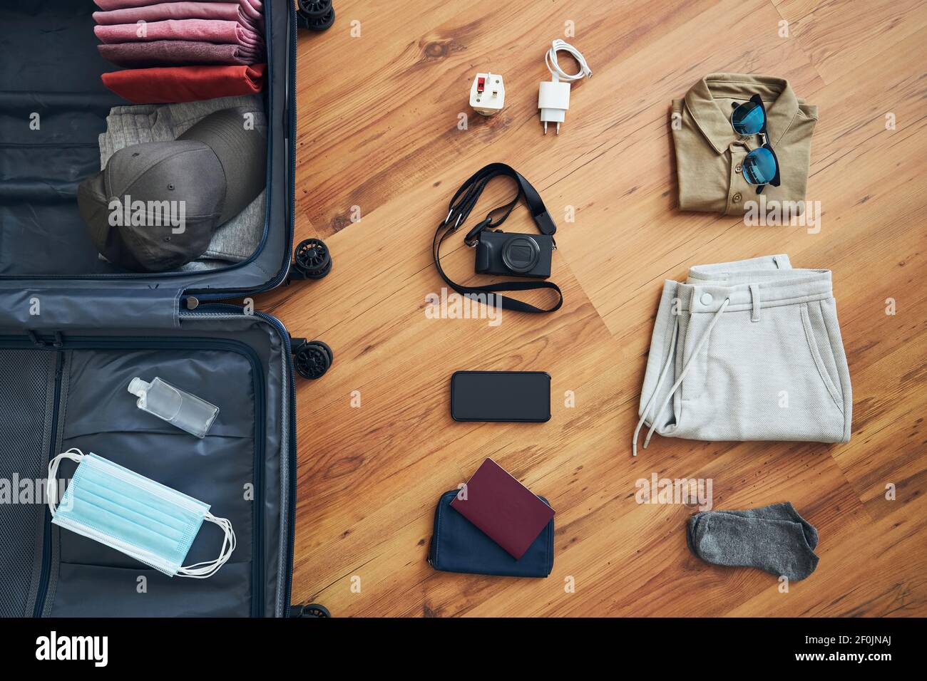 Preparándose para viajar en una nueva normalidad. Maleta embalaje con ropa de verano, teléfono inteligente, cámara, pasaporte y objetos para la protección personal - cara mas Fotografía de stock - Alamy