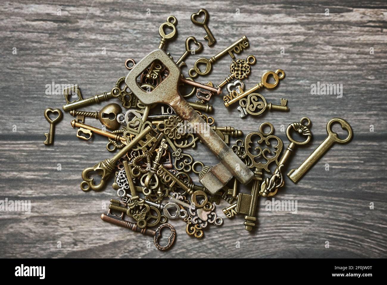 Muchas llaves pequeñas diferentes con símbolos de amor y una vieja llave  oxidada sobre fondo de madera Fotografía de stock - Alamy