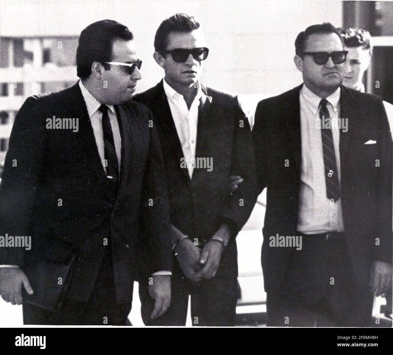 5 de octubre de 1965; el Paso, TX, EE.UU.; Johnny Cash, estrella del país y del oeste, el centro, está flanqueado por un bondman y un Marshall de los EE.UU. Mientras fue transferido de la cárcel del Condado de el Paso al juzgado federal el martes. El efectivo fue detenido el lunes en el aeropuerto internacional y acusado de importar y ocultar más de 1.000 pastillas de pepa y tranquilizantes. El bono era de $1.500. Crédito obligatorio: El Paso Times via USA TODAY NETWORK/Sipa USA Foto de stock