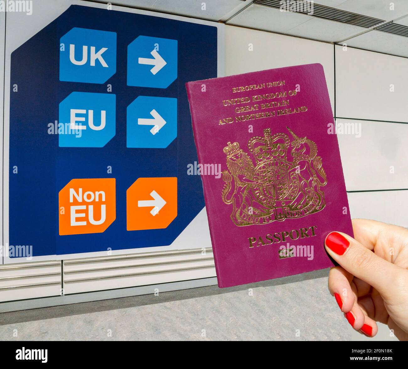 Mano sosteniendo el pasaporte del Reino Unido delante del cartel que indica Titulares de pasaportes de la UE y de terceros del Reino Unido - tema del Brexit Foto de stock