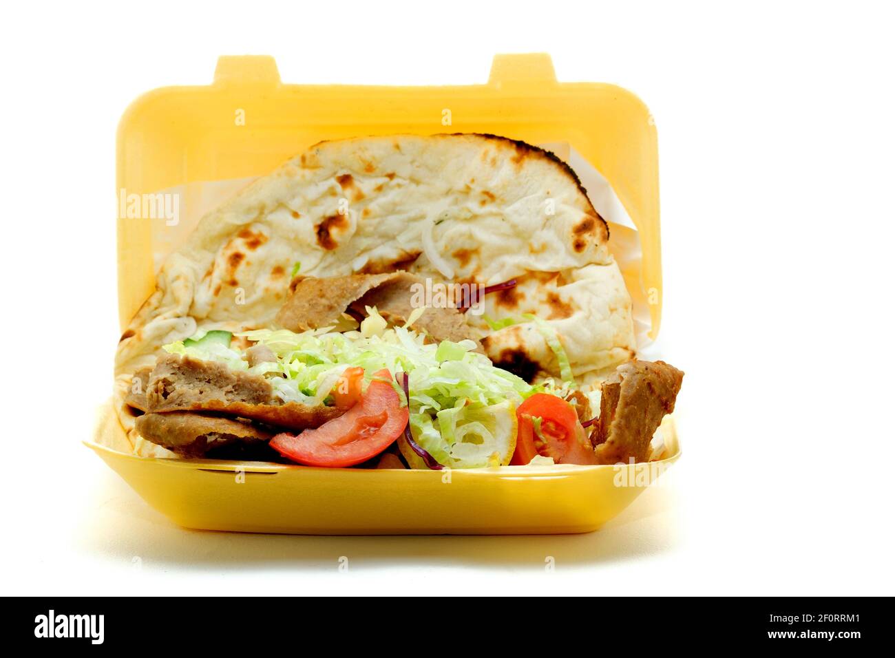 Un Doner Kebab para llevar, o kebab donador, servido con ensalada y envuelto en un pan Nan. El kebab se ha vendido en un contenedor de poliestireno desechable. Foto de stock