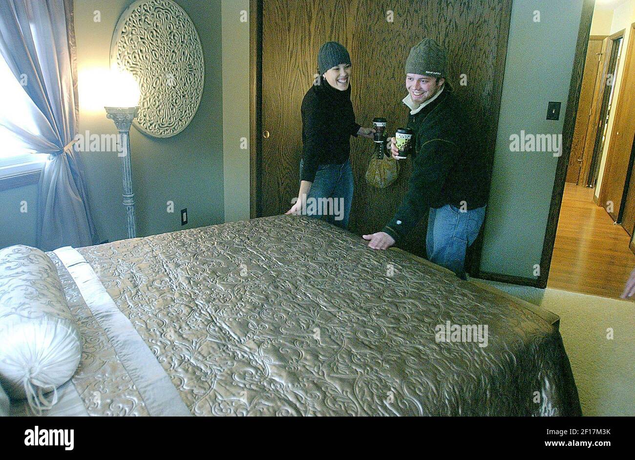 Meghan Greeley, de izquierda, y su novio Pride Jager, ambos de Duluth, Minnesota, sienten la textura de la cama esparcida en el dormitorio principal de la casa que la amiga de Greeley, Beth Johnson, compró, actualizó y luego amueblado. Johnson está vendiendo la casa, que ahora está completamente amueblada y decorada, como un negocio combinado, la hipoteca más los muebles. (Foto de Amanda Odeski/Duluth News-Tribune/KRT) Foto de stock