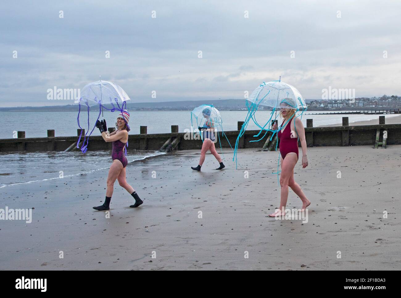 Día Internacional de la Mujer (IWD) - 8th de marzo de 2021.Portobello, Edimburgo, Escocia, Reino Unido. Pequeños grupos de mujeres tomaron un baño para marcar el IWD, diferente de 2020 cuando más de 300 mujeres llegaron a la costa. Foto: Damas de la base Multi-Cultural de la Familia, se han vinculado con el evento de recaudación de fondos #IWDSWIM2021 Wild Swimming Stories para recaudar fondos para las mujeres afectadas por la violencia basada en el Género y marcan la ocasión con brollies Jellyfish. Foto de stock