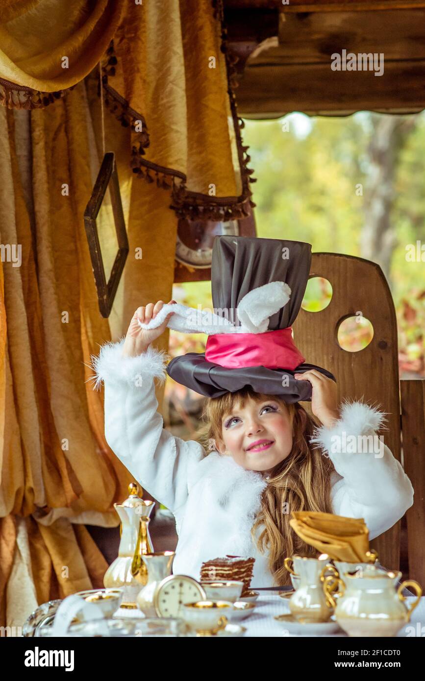 Un poco de hermosa chica sujetando cilindro sombrero con orejas como un  conejo por encima de la cabeza en la mesa Fotografía de stock - Alamy