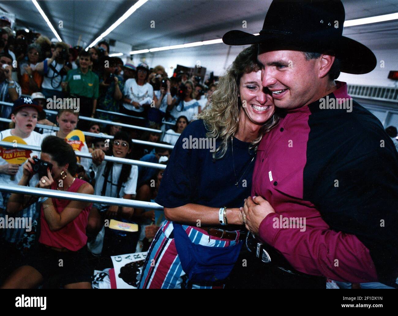 10 de junio de 1993; Nashville, TN, EE.UU.; North Carolinian Iris Wasen lugar recibe un gran abrazo de Garth Brooks en su stand de la Feria de fans en el recinto ferial del estado mientras cientos de fans esperan su turno detrás de él. Crédito obligatorio: El Tennessean a través de EE.UU. HOY RED / Sipa EE.UU. Foto de stock