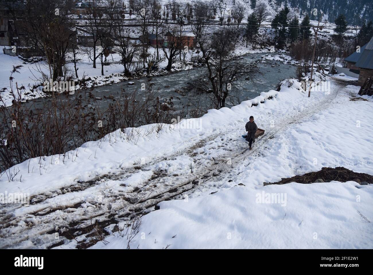 Un niño Baqarwal tira de su trineo de nieve fuera de su casa después de una Nevada en Ganderbal Cachemira. El clima mejora en Cachemira India después de 3 días, la temperatura del día aumenta mientras que la temperatura de la noche continúa bajándose. (Foto de Irnes Abbas / SOPA Images/Sipa USA) Foto de stock