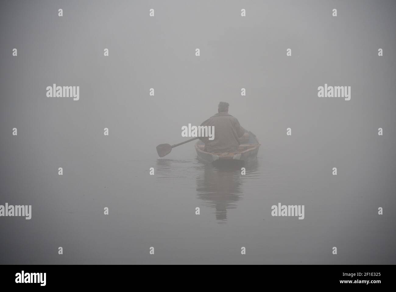 Un hombre hace filas en su barco en el lago Dal durante una densa niebla en Srinagar. Las temperaturas nocturnas a través de Cachemira cayeron por debajo del punto de congelación. Mañana frío y niebla densa mantuvo la mayoría de los cachemiros en el interior hasta que un sol débil comenzó a luchar su camino a través de una capa delgada de nubes de invierno. (Foto de Irnes Abbas / SOPA Images/Sipa USA) Foto de stock