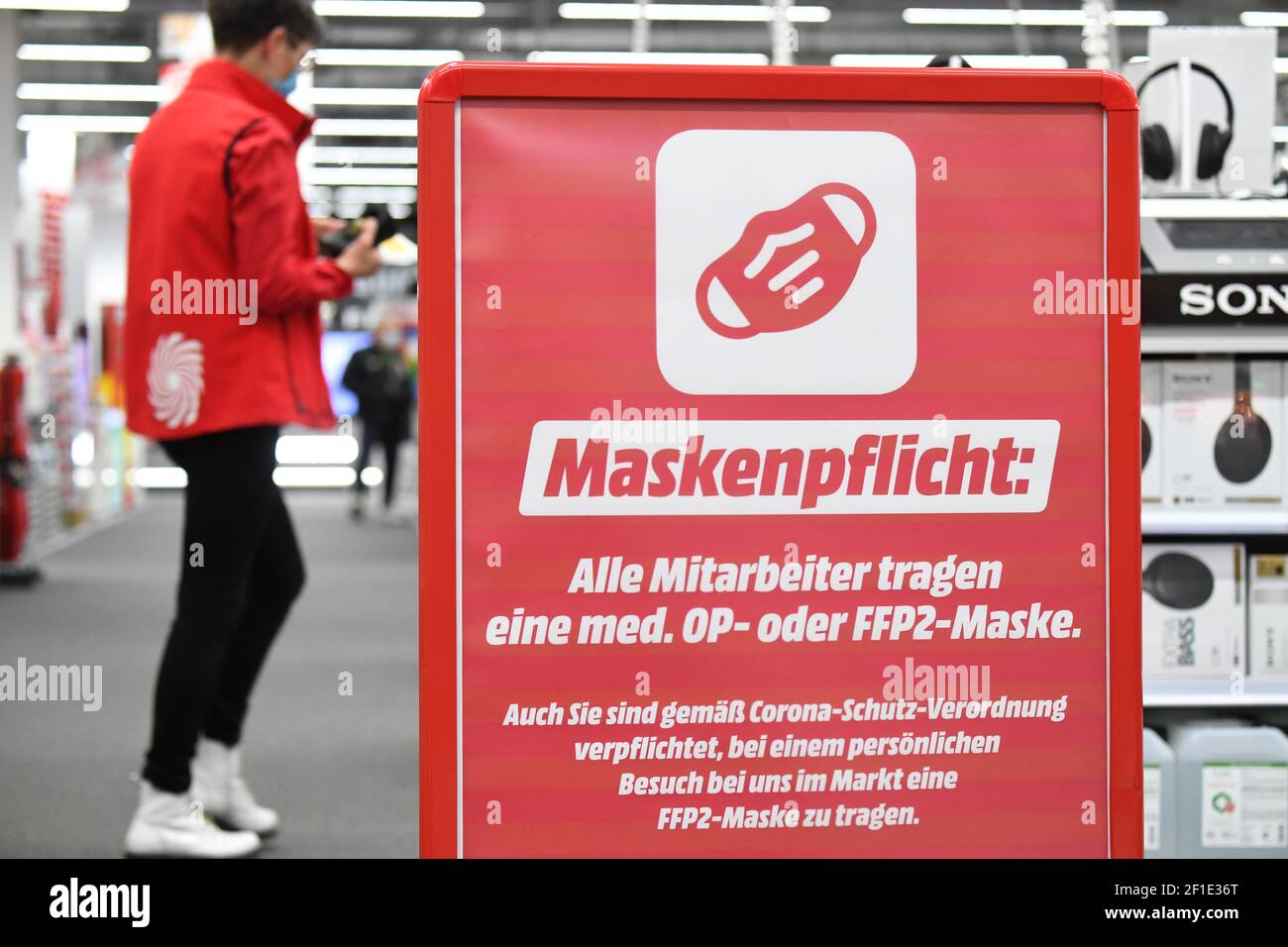 Stralsund, Alemania. 08th de marzo de 2021. Un empleado pasa por delante de  una señal que dice "requisito de la petición" en una sucursal de la cadena  de comercio electrónico Media Markt.