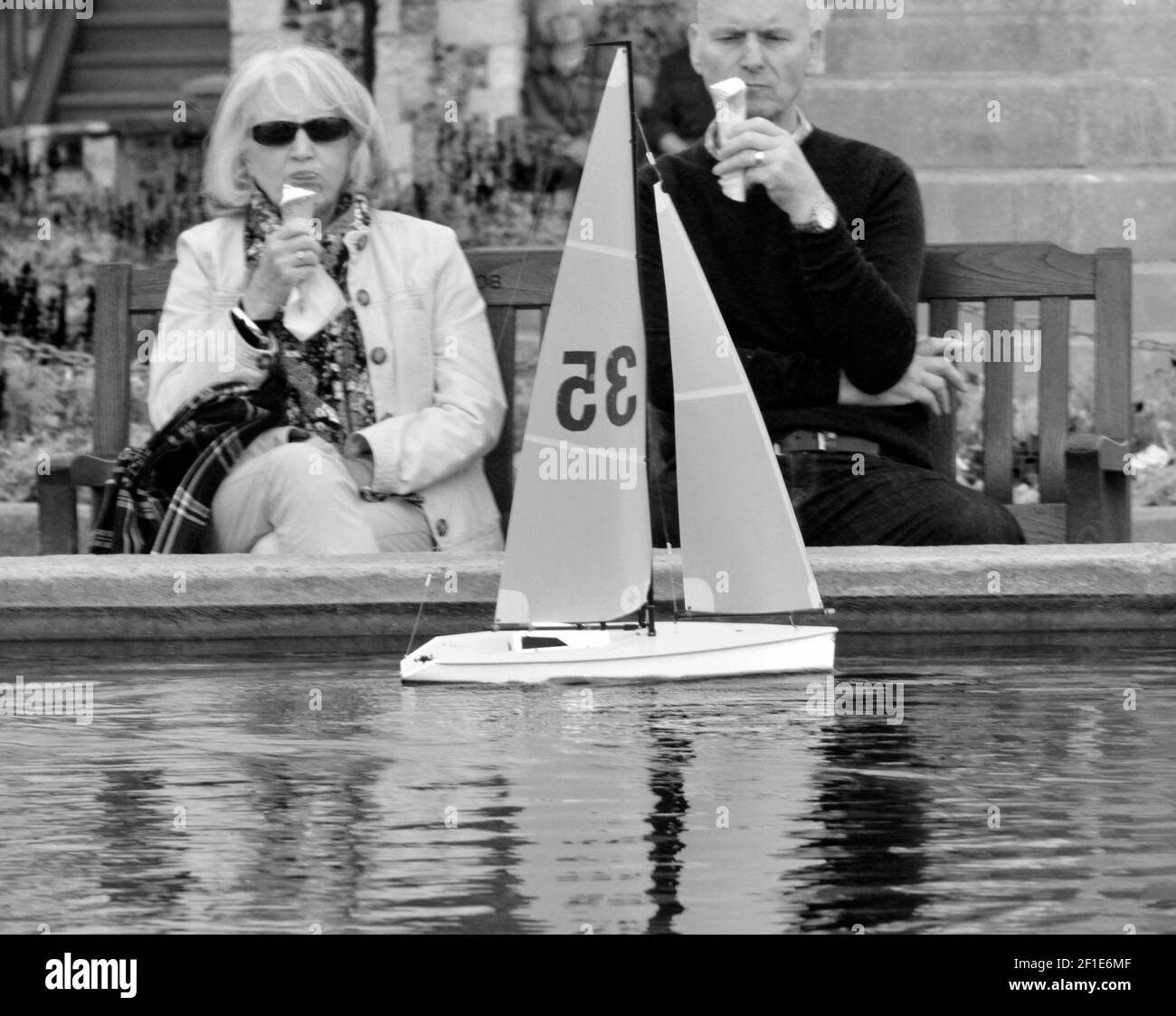 hombre y mujer comiendo helado observando modelo de velero en curso aldeburgh suffolk inglaterra Foto de stock