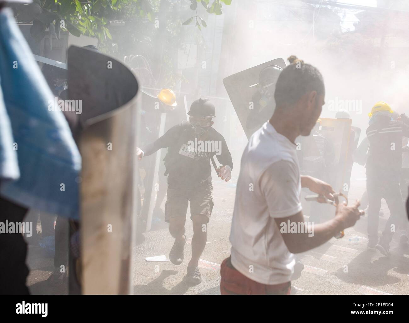 Los manifestantes reaccionaron después de que la policía antidisturbios disparara cartuchos de gas lacrimógeno durante una manifestación contra el golpe militar.la policía de Myanmar atacó a los manifestantes con balas de goma, municiones vivas, gas lacrimógeno y bombas de aturdimiento en respuesta a los manifestantes contra el golpe militar el lunes. Las fuerzas de seguridad mataron a dos manifestantes en Myitkyina, estado de Kachin, procedentes de fuentes locales. Un total de 1758 personas han sido perseguidas, 1440 de ellas todavía en prisiones militares de Myanmar y 60 personas han sido asesinadas desde el comienzo de las protestas contra el golpe militar. Los militares de Myanmar detuvieron a la Consejera de Estado de Myanmar Aung Foto de stock