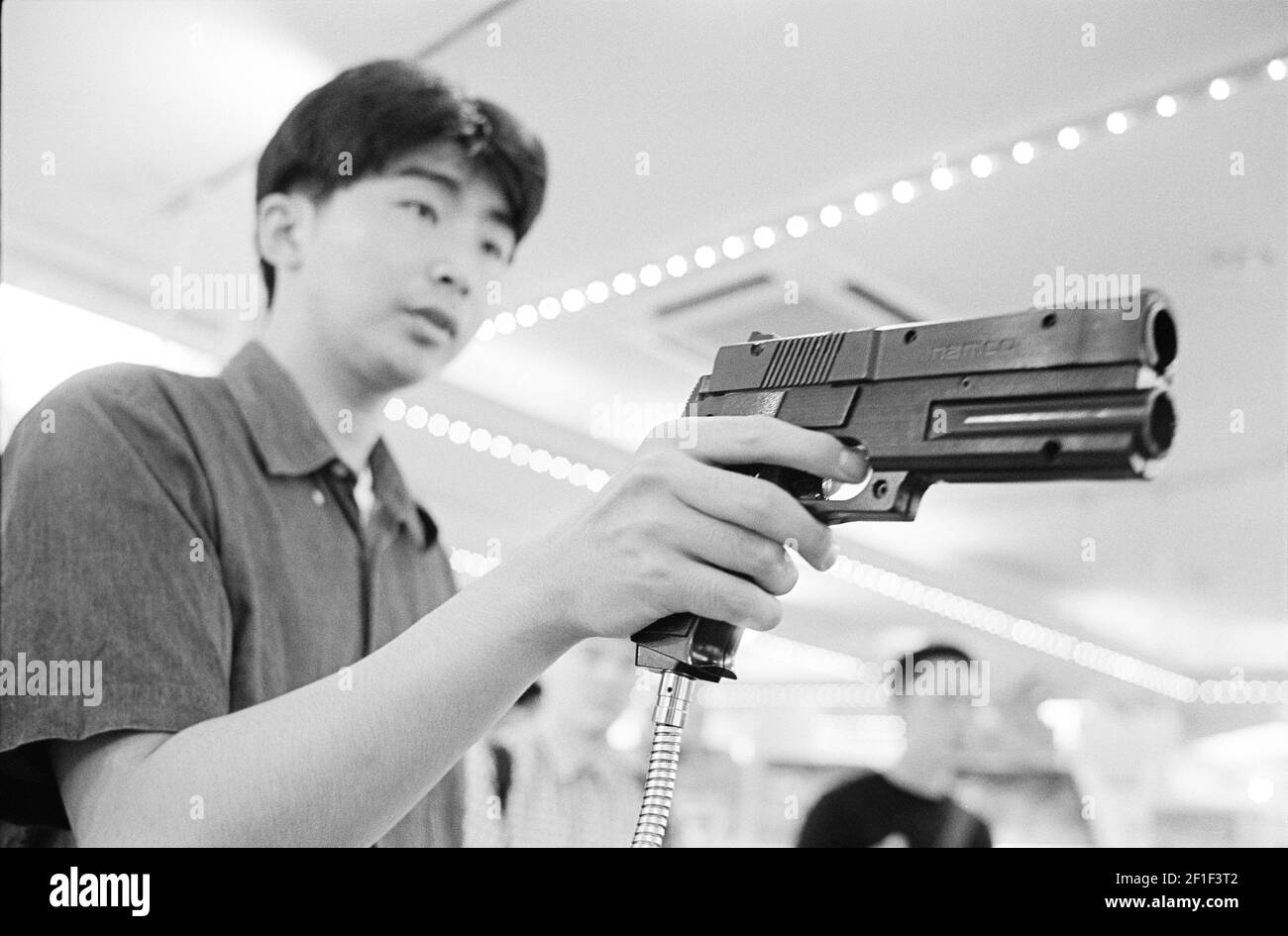 Hombre jugando un juego de ordenador con un arma Tokio, Japón, 1998 Foto de stock