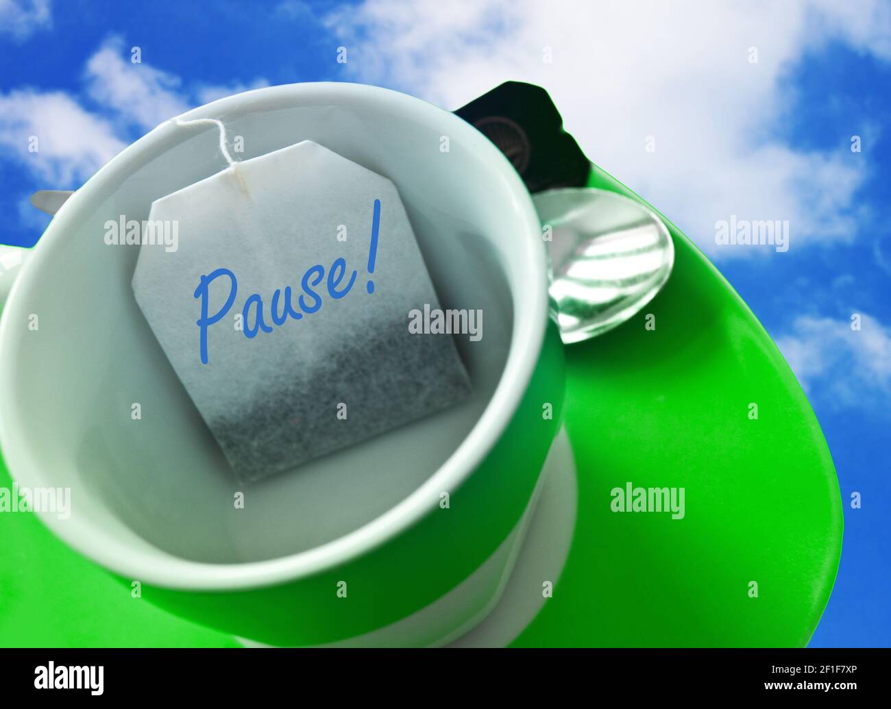 Grüne Tasse mit Teebeutel auf Himmel Pausa descanso Foto de stock
