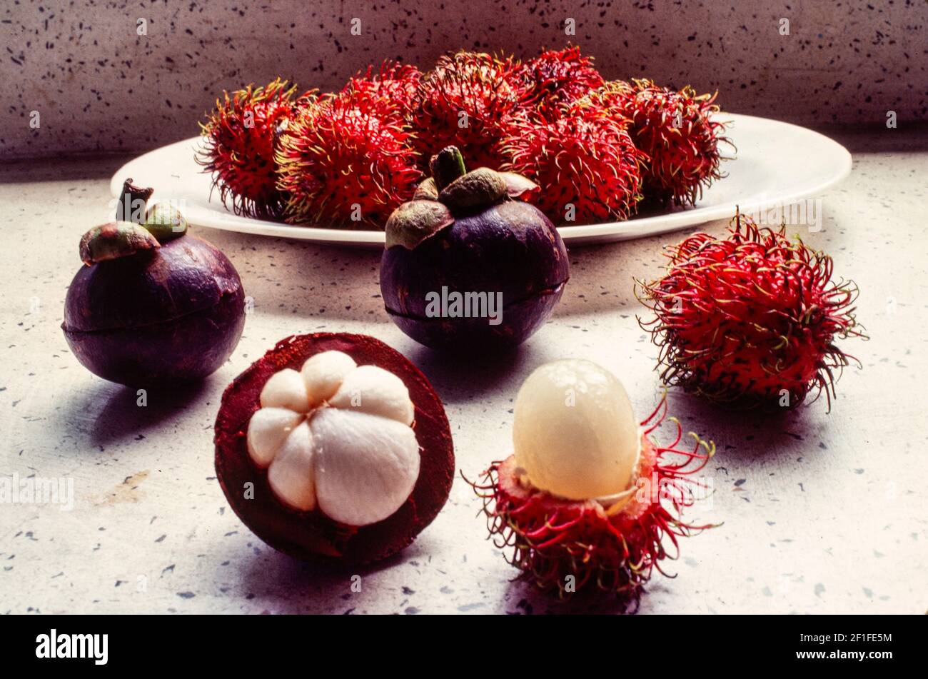 Frutas vietnamitas, el mangostán (Mang Cut) izquierda y el rambutan (Chom Chom) o lichee peludo, Ciudad Ho Chi Minh, Vietnam, junio de 1980 Foto de stock