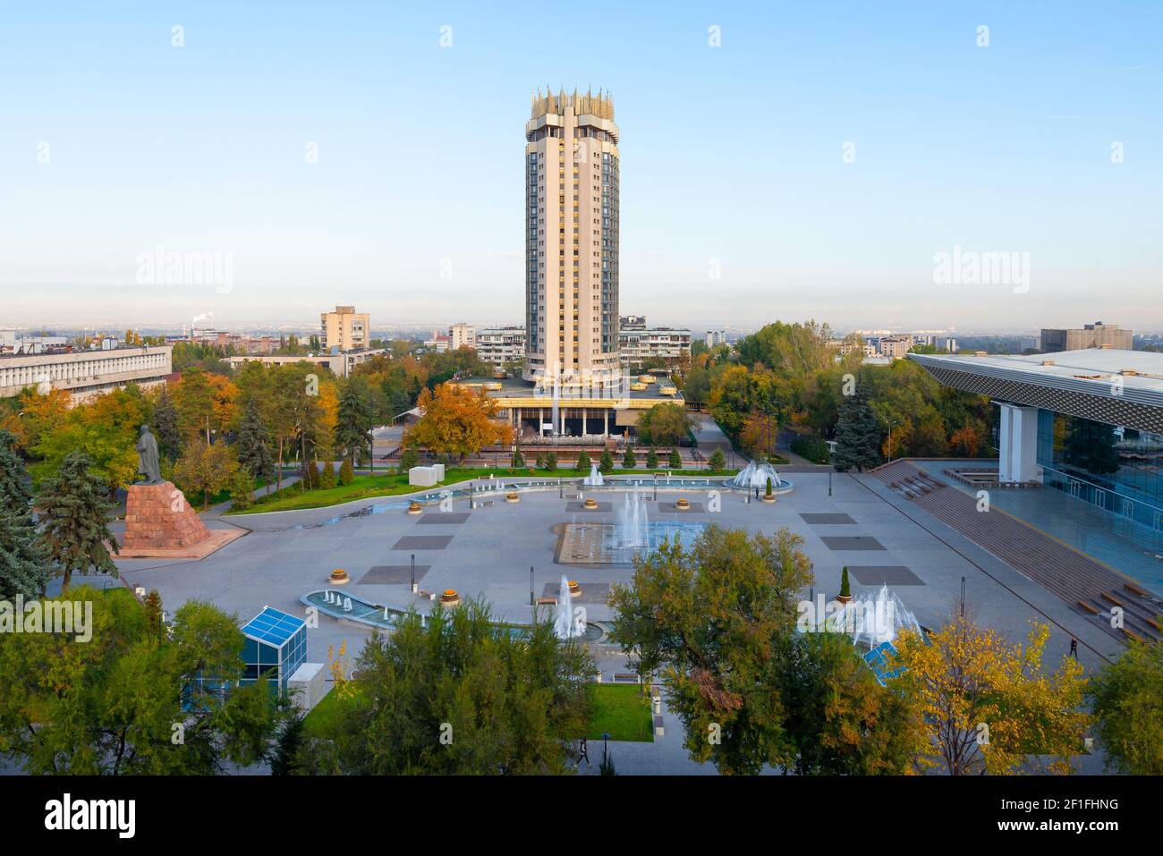 Kazajstán Hotel torre en la Plaza Abai, Almaty. Vegetación y fuentes de agua en la Plaza Abay frente al Palacio de la República. Foto de stock