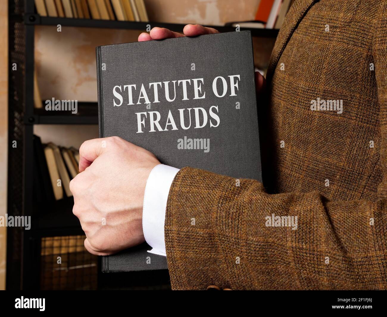 El abogado toma un libro del estatuto de fraude de la estantería. Foto de stock