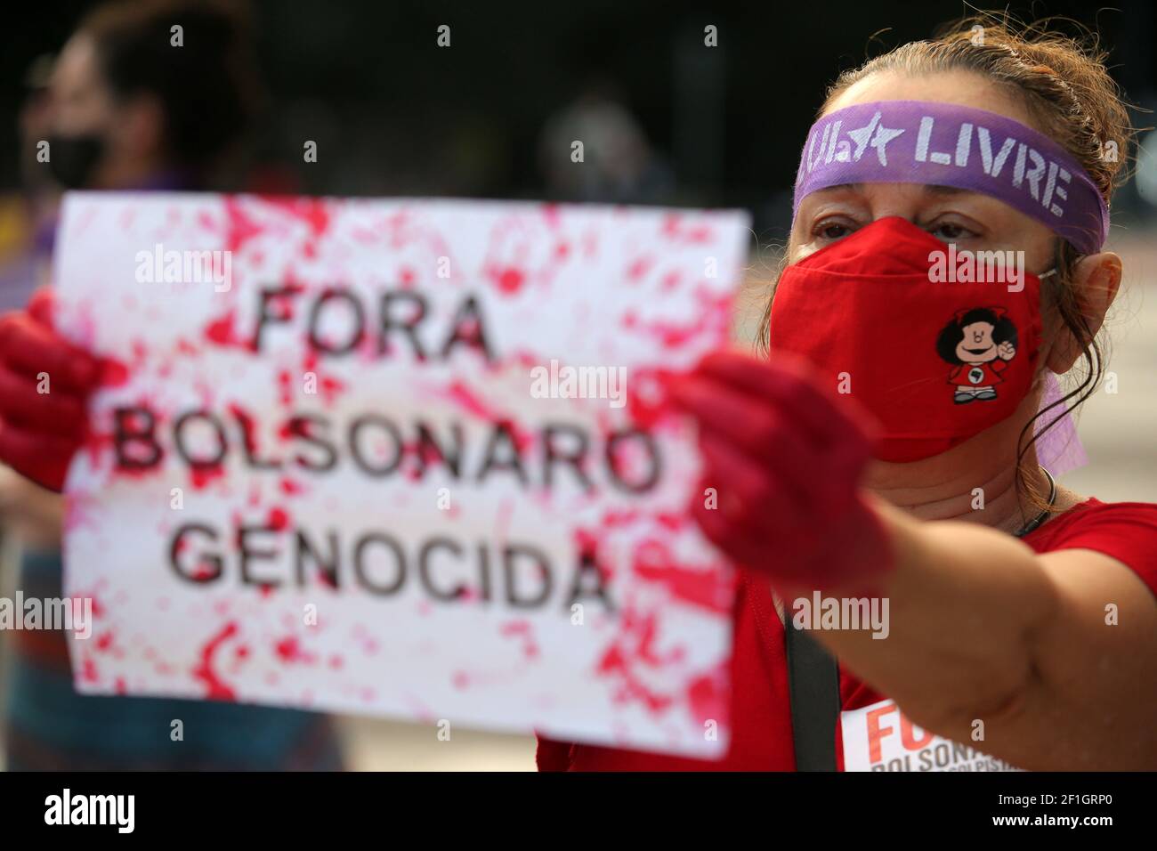 Una activista muestra un cartel que dice: "Genocida Bolsonaro Out" mientras  participa en una manifestación para conmemorar el día Internacional de la  Mujer en Sao Paulo, Brasil, 8 de marzo de 2021.