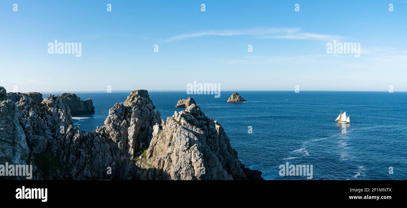 velero de madera frente a la costa rocosa salvaje de Bretaña en Francia occidental Foto de stock