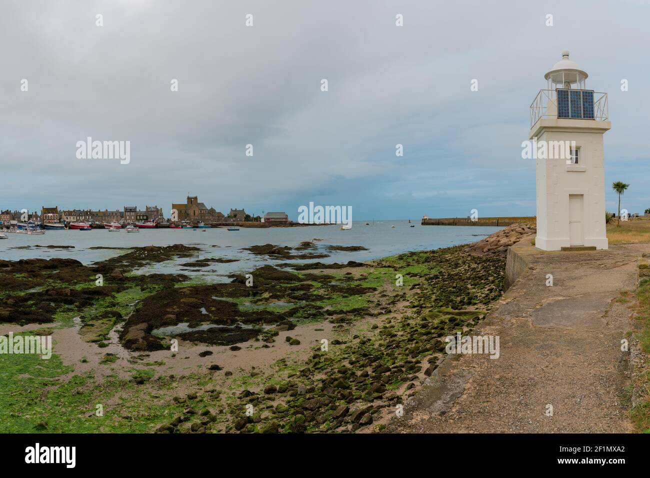 El faro del puerto de Barfleur y el puerto en la marea baja la noche Foto de stock