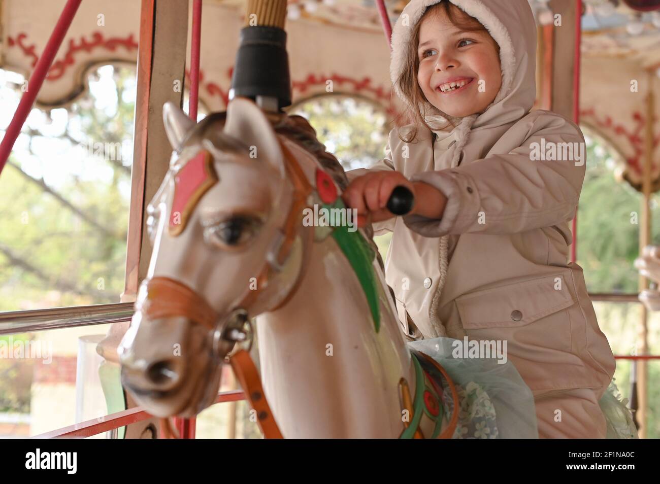 La chica en ropa brillante cabalga sobre el carrusel de vacaciones. Bebé  feliz es divertirse Fotografía de stock - Alamy