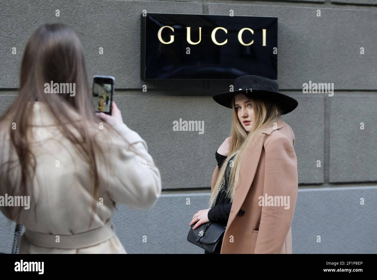 Una mujer joven posan para una foto delante del logo de Gucci, de una casa  de moda de lujo, fuera de una tienda de la Marca Gucci. (Foto de Pavlo  Gonchar /