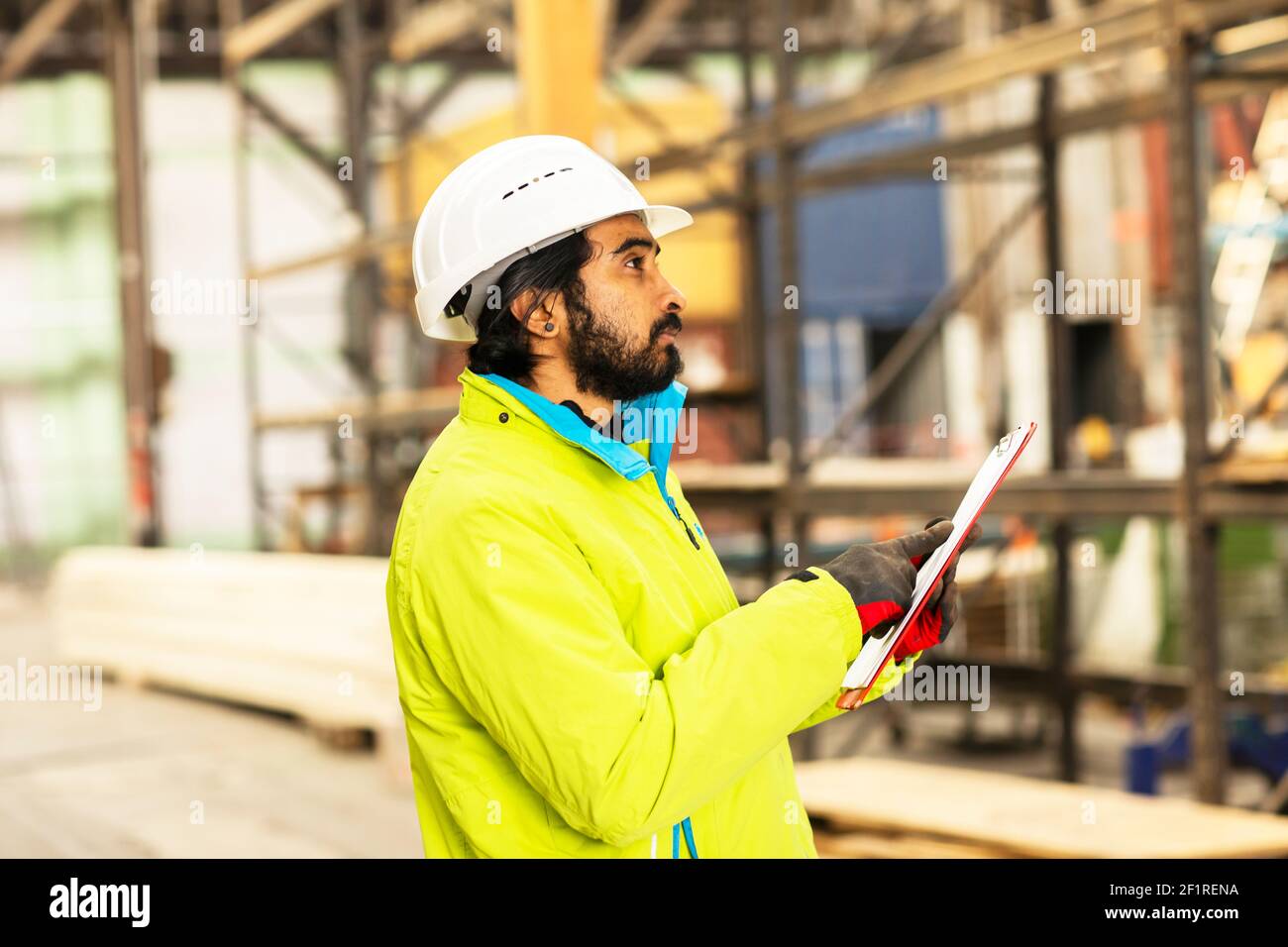 Joven trabajador con casco y barba trabajando en un almacén Foto de stock