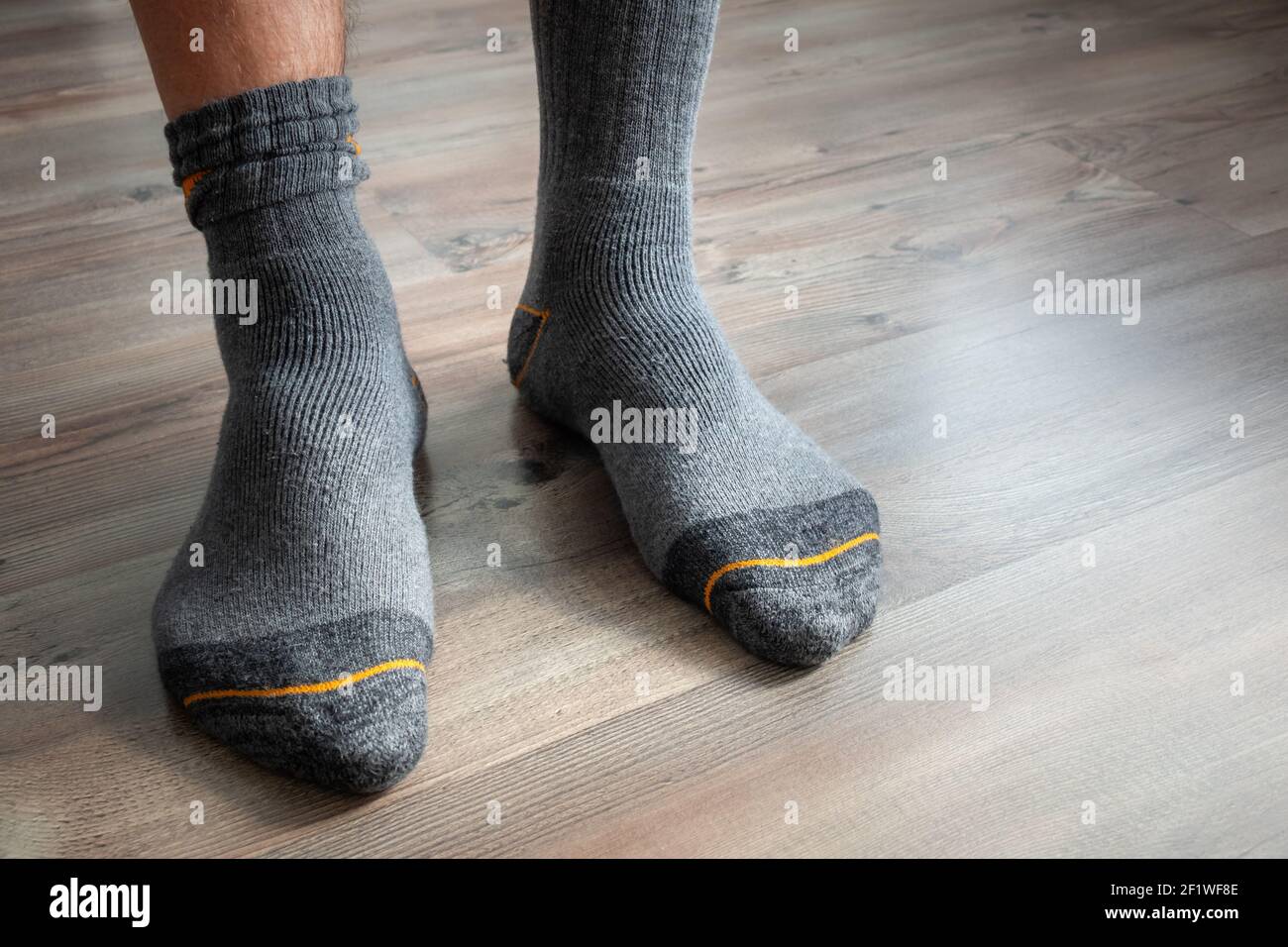 Pies masculinos en calcetines grises sobre un suelo de madera Fotografía de  stock - Alamy