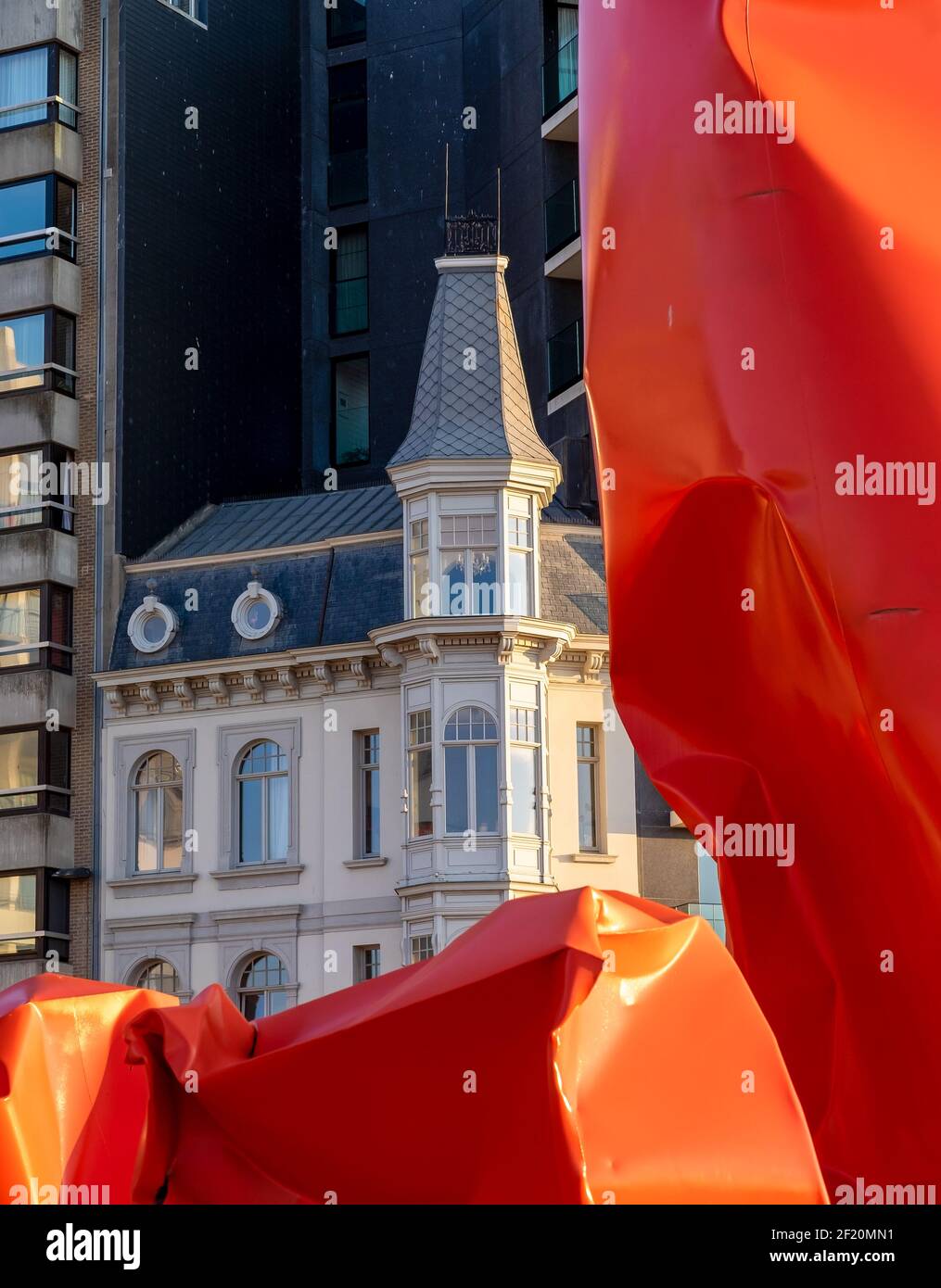 Edificio histórico junto a la obra de arte 'Rock Strangers' de la artista belga Arne Quinze. Foto de stock