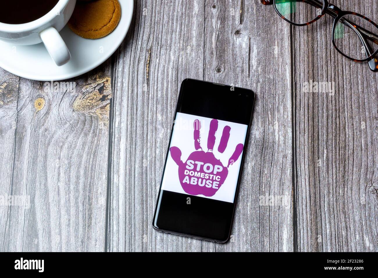 Un teléfono móvil o celular colocado sobre una madera Tabla con un logotipo  de Stop Domestic abuse en la pantalla Fotografía de stock - Alamy