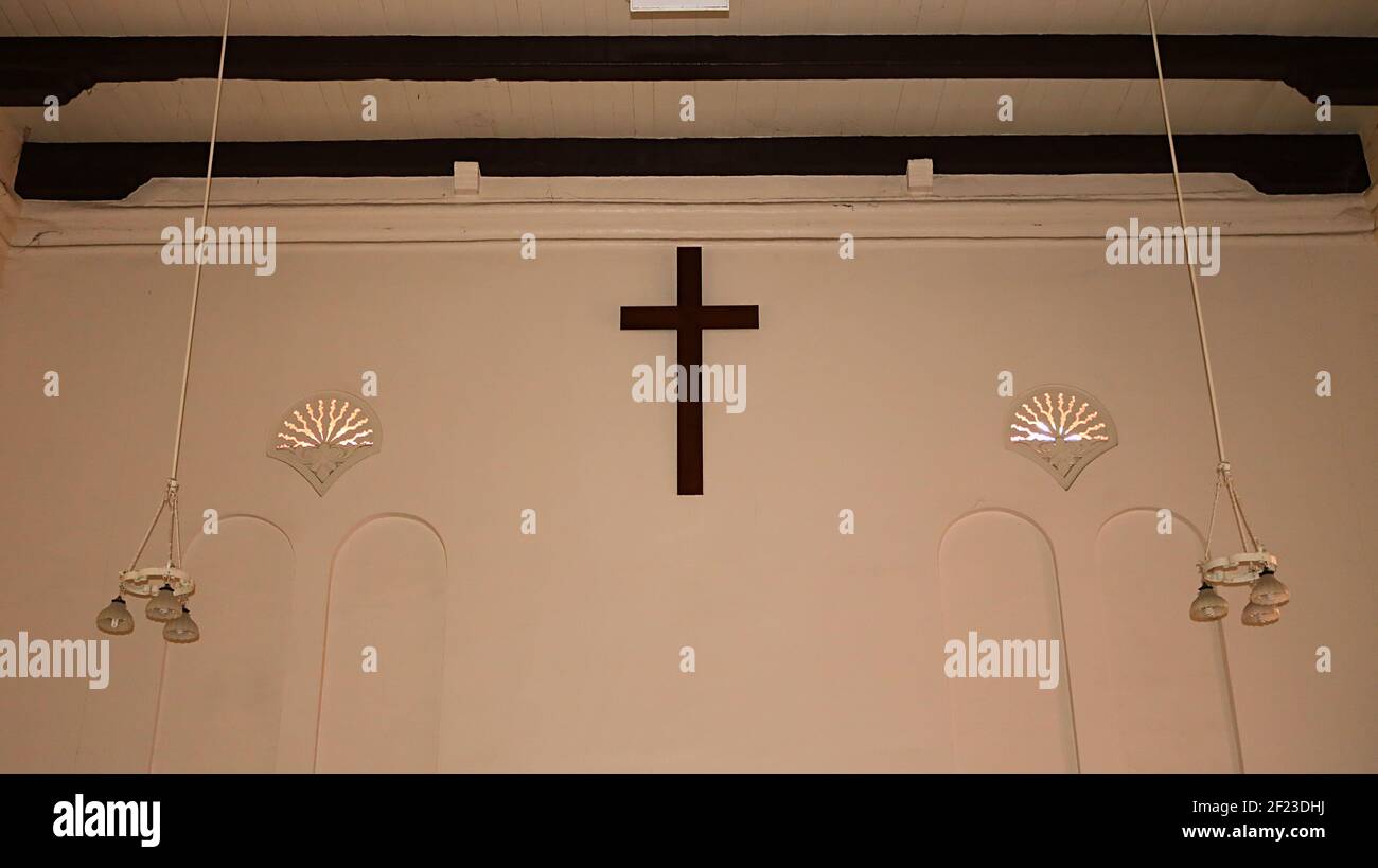 Muro detrás del altar: Cruz colgada en la pared, luces colgantes y vigas de madera horizontales en la pared de la Iglesia de Cristo en Malaca (Melaka) Malasia Foto de stock