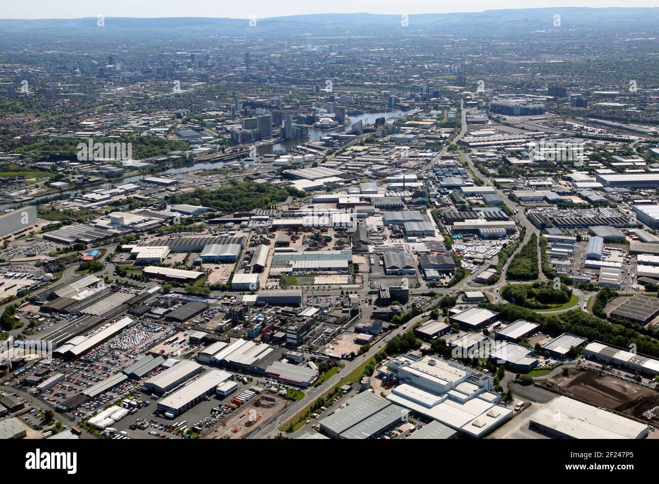 Vista aérea del enorme parque industrial Trafford con El horizonte del centro de la ciudad de Manchester al fondo Foto de stock