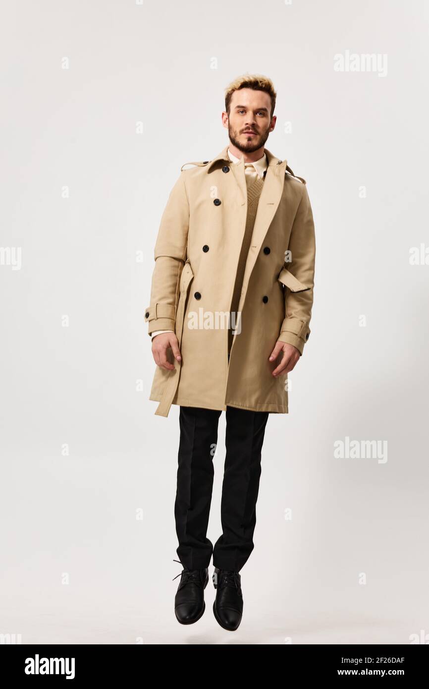 hombre rubio guapo en un abrigo y pantalón beige un fondo claro Fotografía  de stock - Alamy