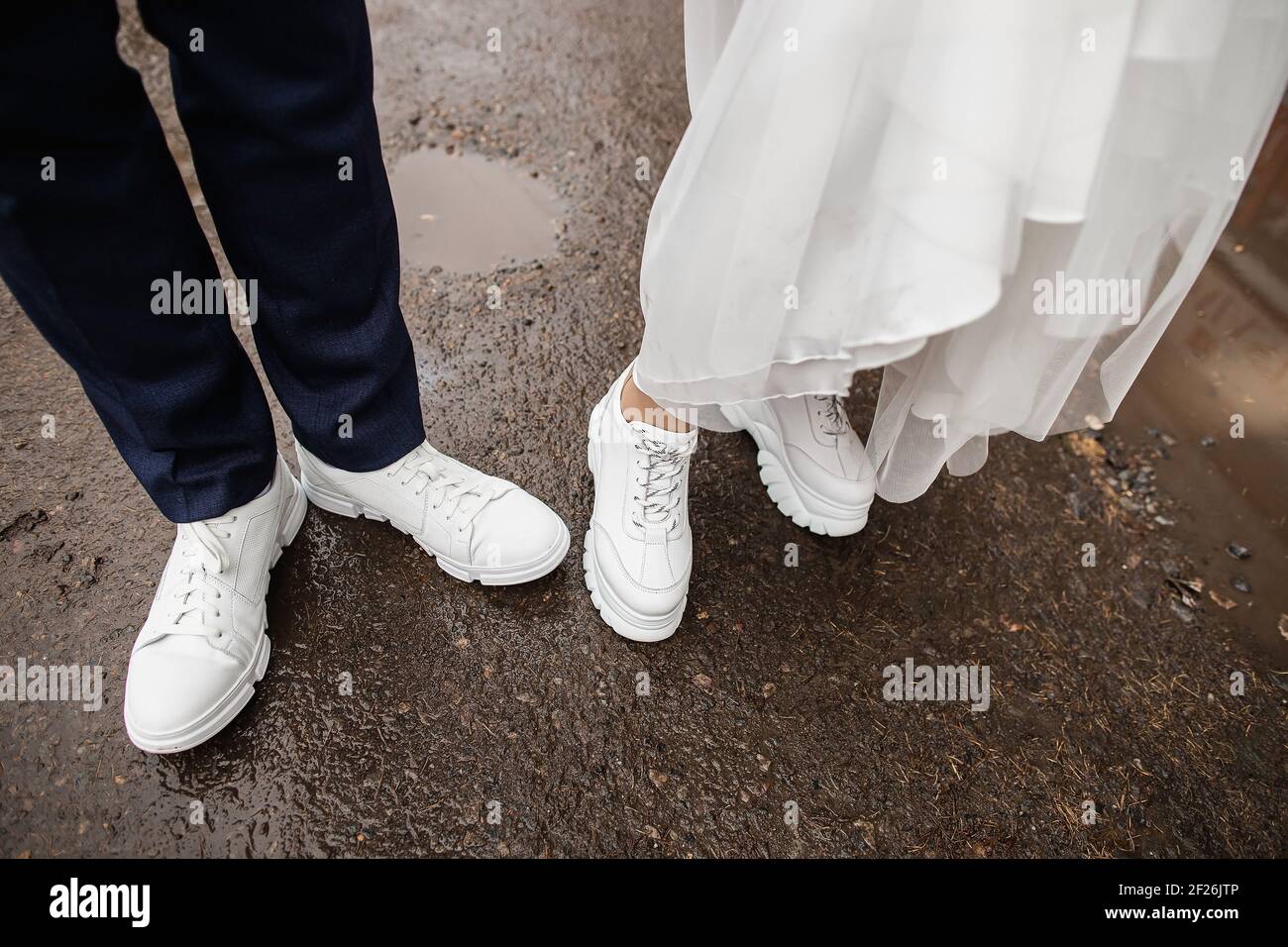 Recién casados en elegantes sneakers blancas en tiempo lluvioso Fotografía  de stock - Alamy