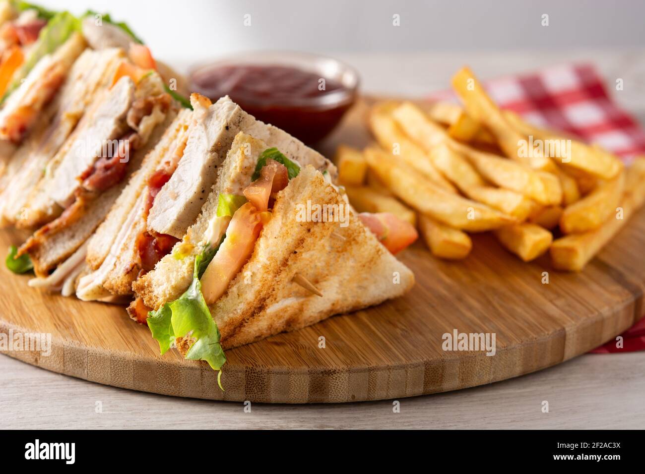 Sándwich club y patatas fritas con salsa de ketchup en madera tabla Foto de stock