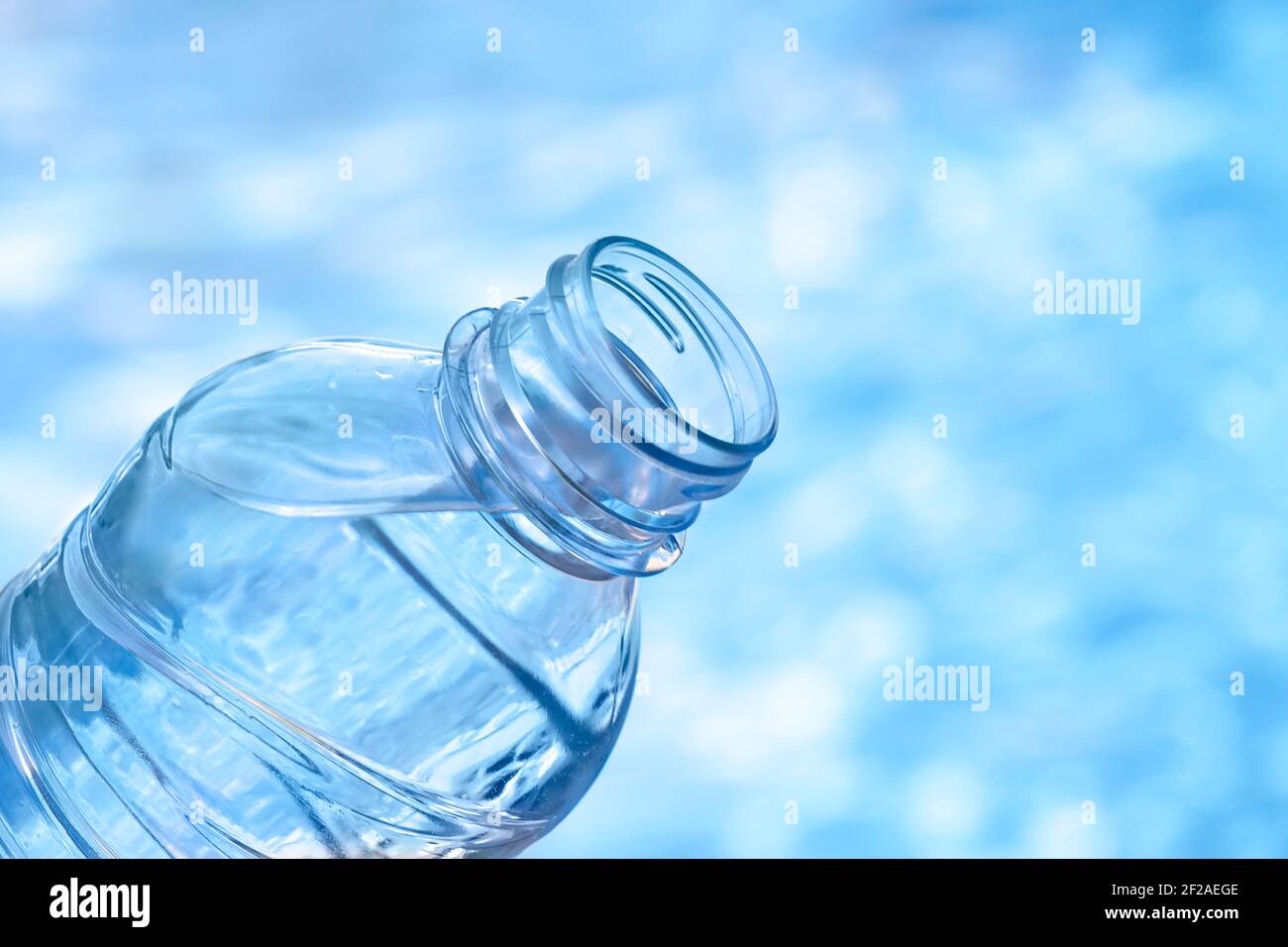 Botella de plástico de agua contra fondo azul de agua Foto de stock