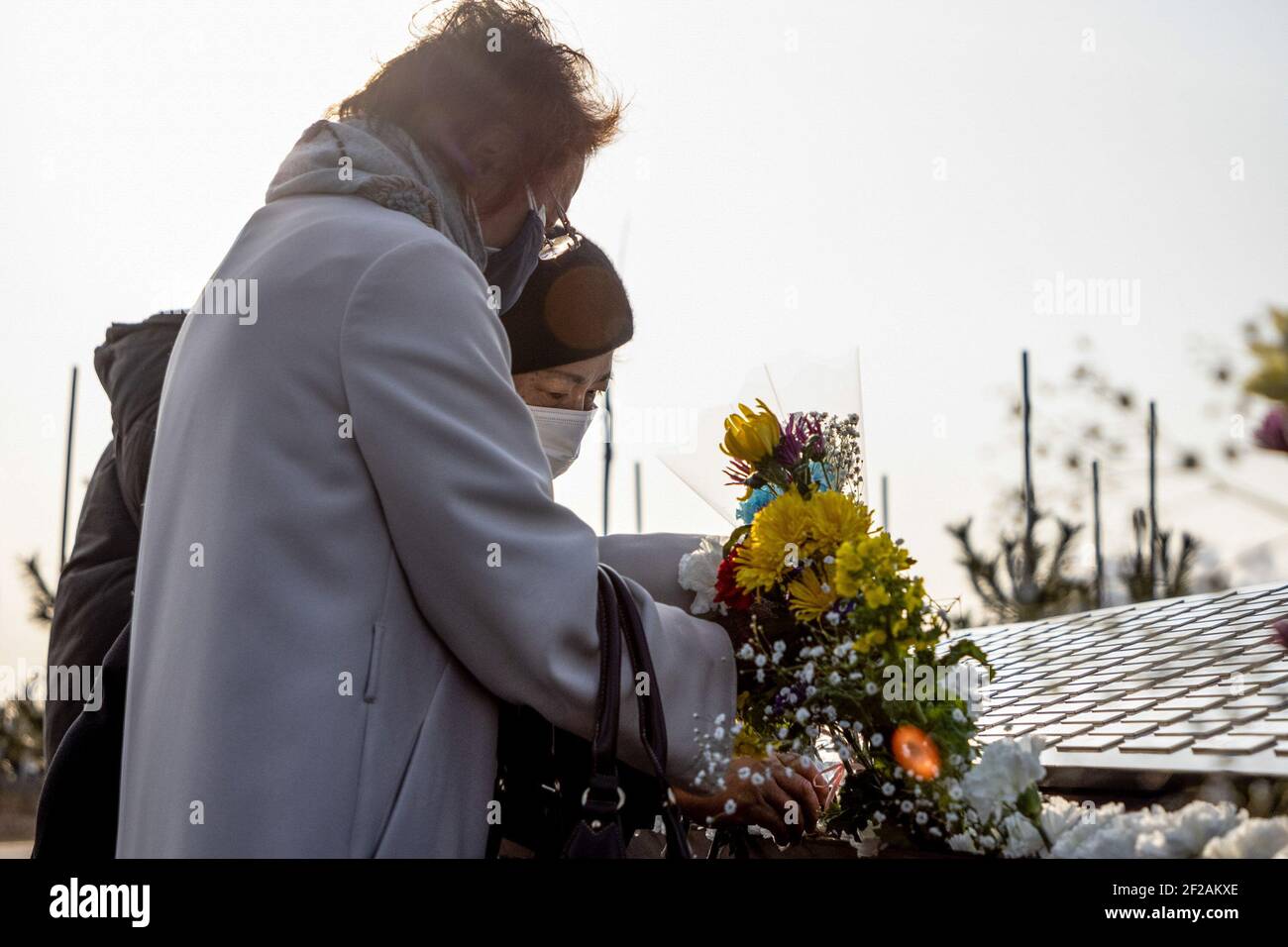 Una pareja ofrece flores para sus seres queridos en el parque conmemorativo  abierto en Ishinomaki. Familias y amigos vienen y buscan nombres y ofrecen  flores y pagadores en recuerdo de los seres