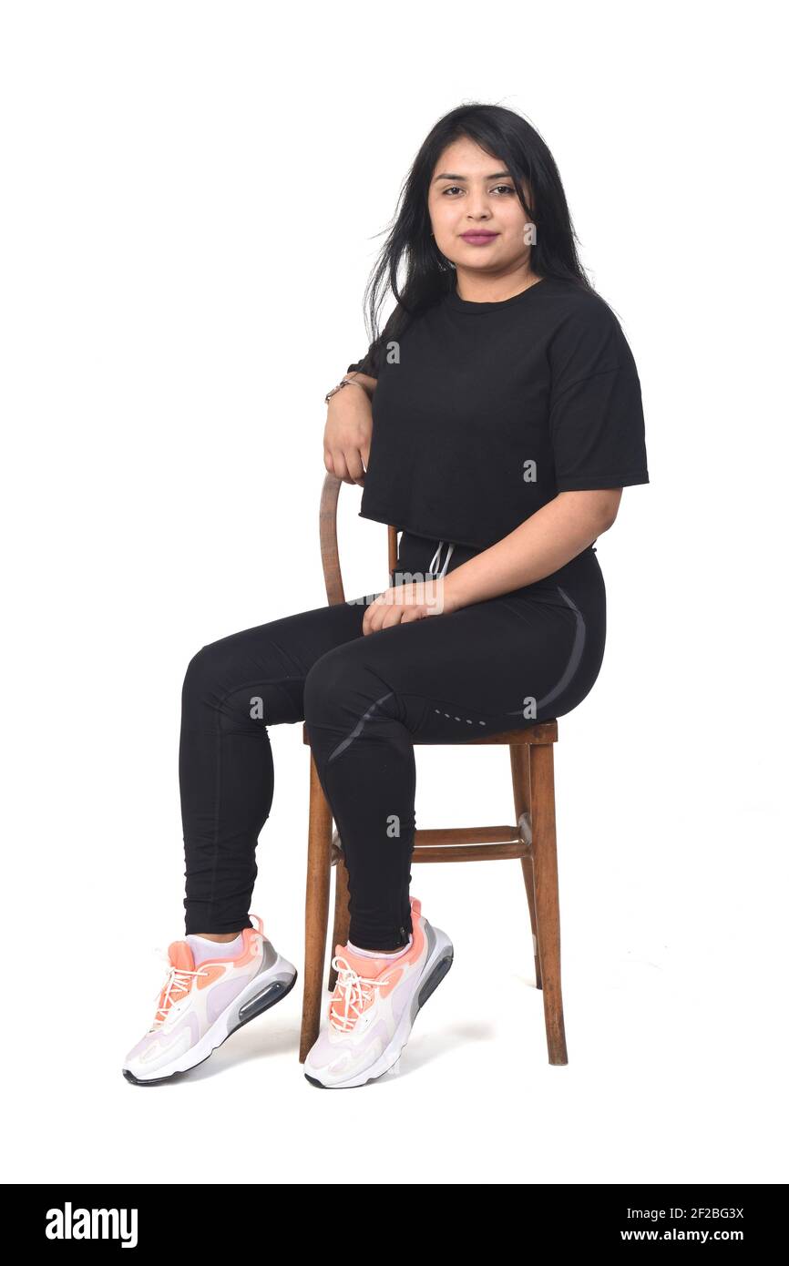 Mujer latina con ropa deportiva sentada de lado sobre fondo blanco  Fotografía de stock - Alamy