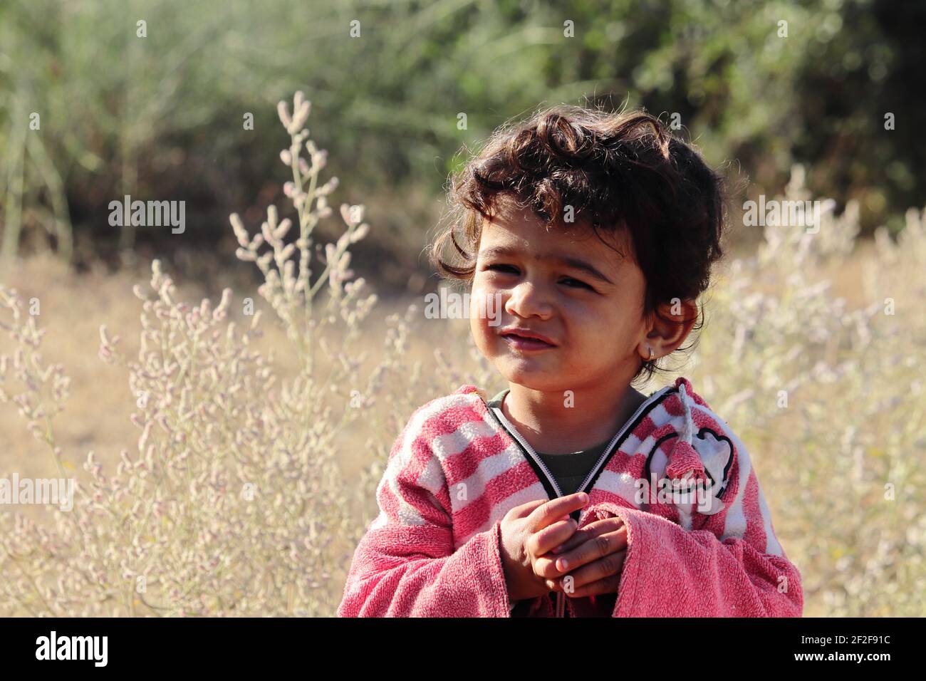 Un niño pequeño de origen indio mirando la cámara con ojos pequeños.concepto para los niños de hoy el futuro de mañana, recuerdos de la infancia, sonrisa en la cara, Foto de stock