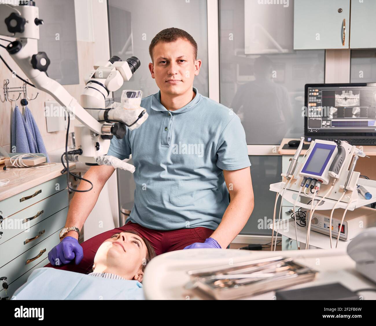 Joven dentista varón sentado paciente de cabecera en el consultorio dental  Fotografía de stock - Alamy
