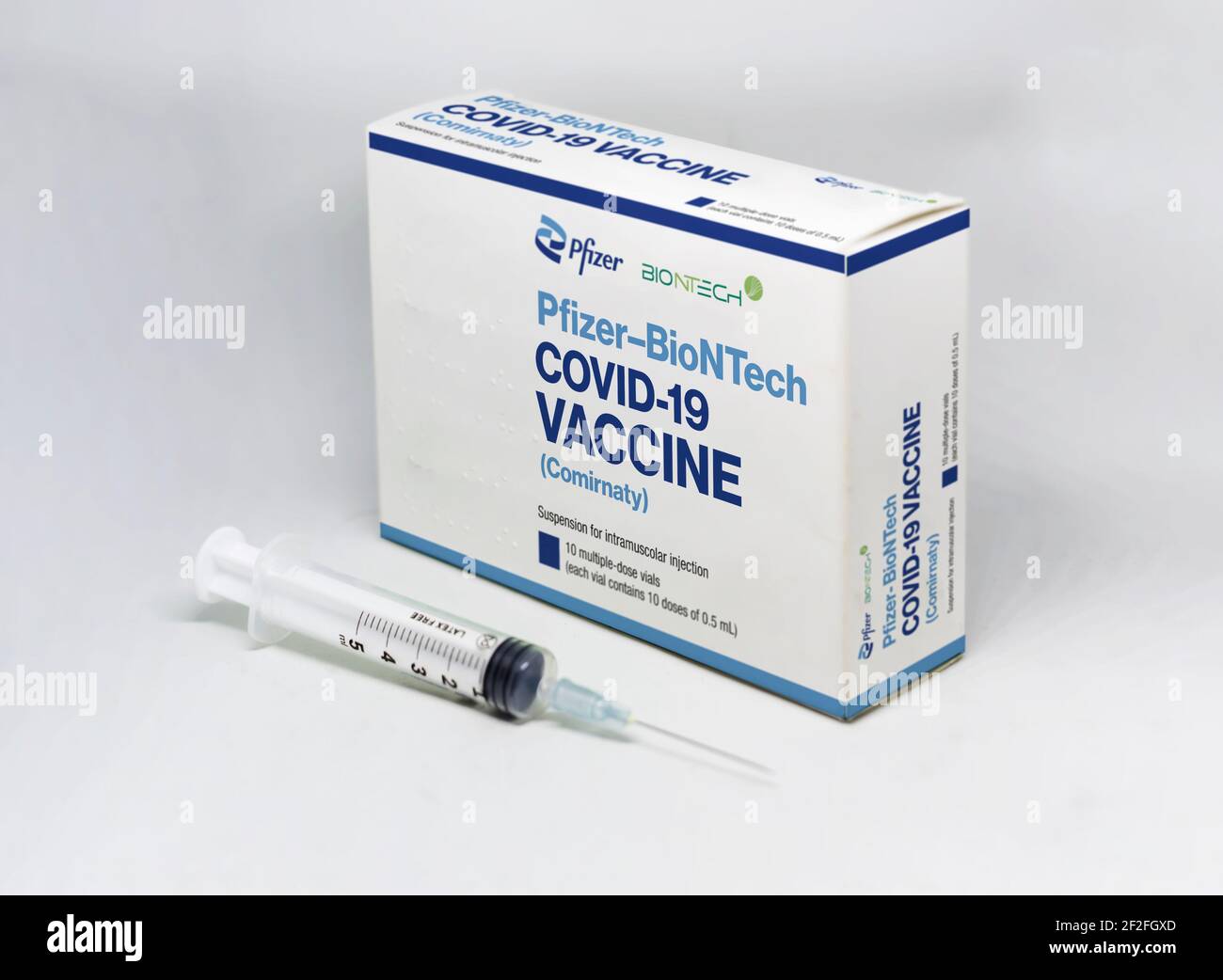 Nueva York EE.UU., febrero de 5th 2021: Una jeringa junto a la caja de la vacuna Pfizer BioNTech Covid-19 aislada sobre fondo blanco. Salud y prevención. Foto de stock