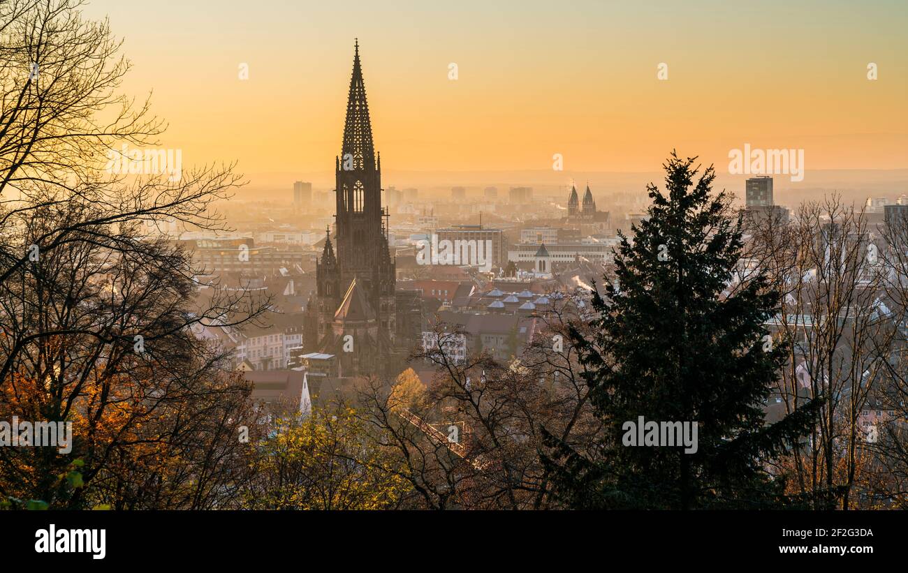 Alemania, Freiburg im Breisgau, Magical naranja puesta de sol cielo sobre el horizonte de la hermosa ciudad y muenster en el frío día de invierno Foto de stock