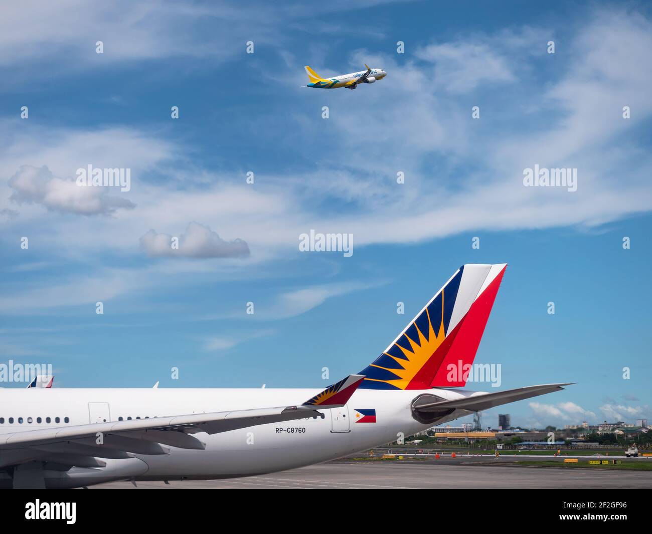 Philippine Airlines Airbus A330 en la Terminal 2 del Aeropuerto Internacional Ninoy Aquino en Manila, con Cebu Pacific Airbus A320 volando por encima. Foto de stock