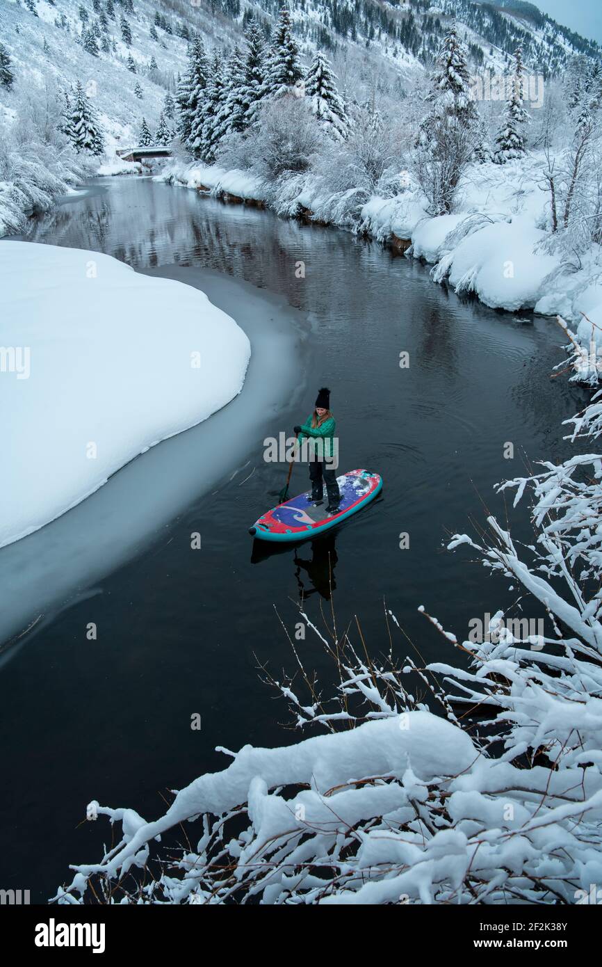 Mujer paddleboarding en el río durante el invierno Foto de stock