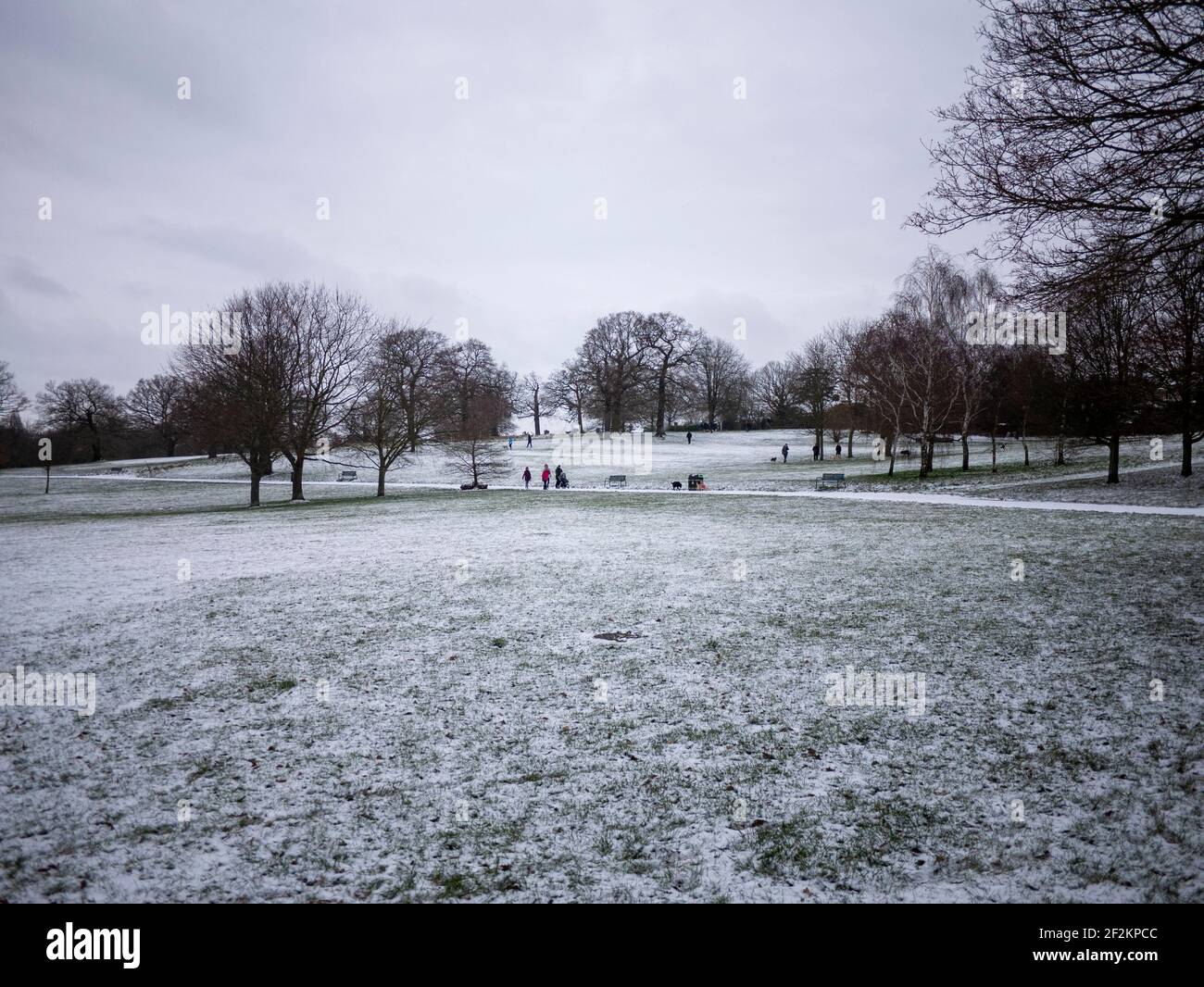 Highams Park Londres, el Highams Park en Highams Park, Londres durante la nieve de invierno, con gente caminando entre los árboles Foto de stock