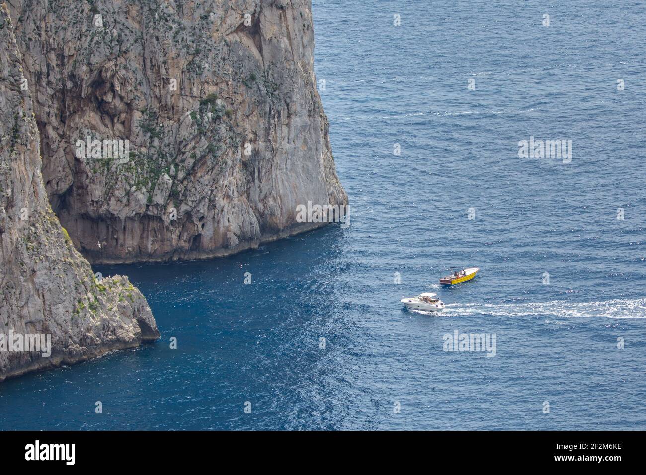 Barcos de excursión en las rocas Faraglioni. Vista de las famosas rocas Faraglioni en el mar Tirreno azul, isla de Capri, Italia Foto de stock