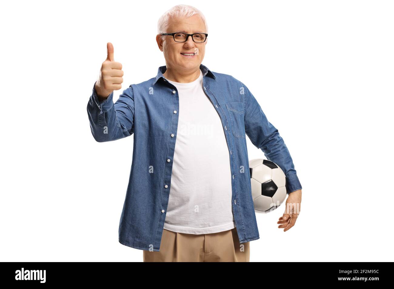 Hombre maduro sosteniendo un balón de fútbol y mostrando los pulgares hacia arriba aislado sobre fondo blanco Foto de stock