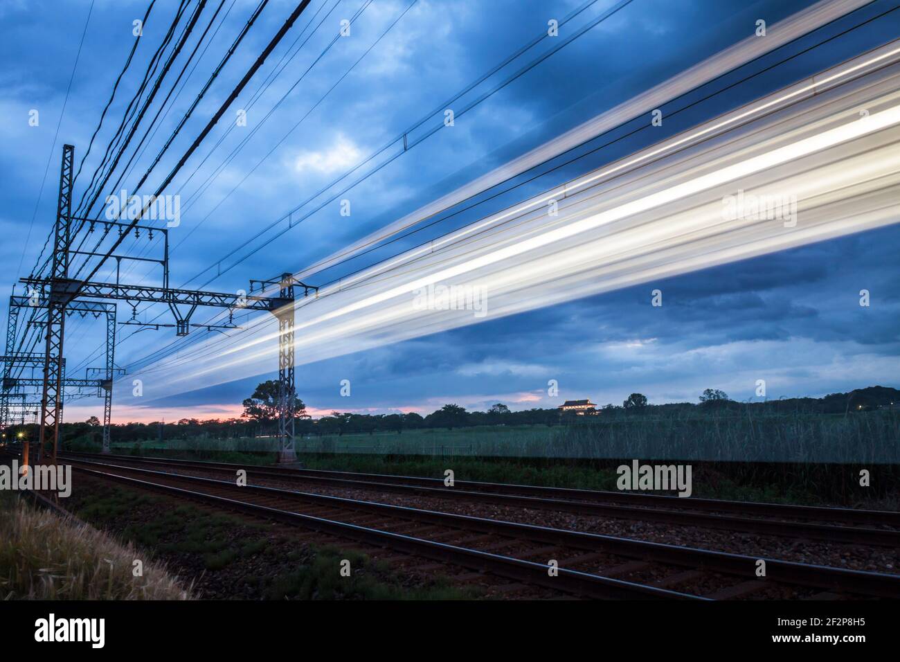 Larga exposición de un tren corriendo por una línea de ferrocarril al atardecer en Nara, Japón Foto de stock