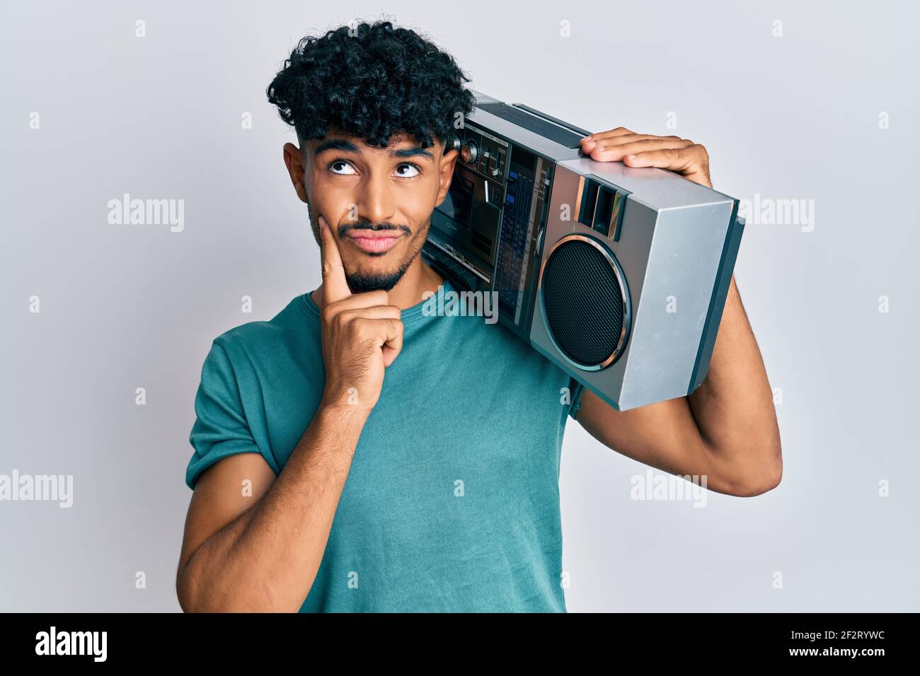 Joven árabe guapo sosteniendo boombox, escuchando música cara seria  pensando en la pregunta con la mano en la barbilla, reflexivo sobre la idea  confusa Fotografía de stock - Alamy