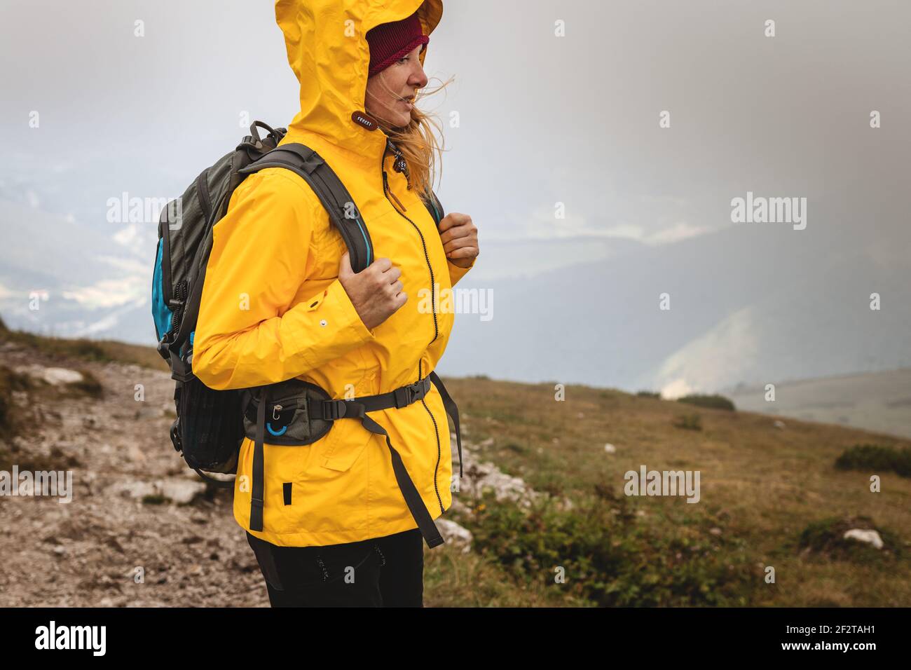 Mujer senderismo en las montañas en clima extremo. Chaqueta impermeable de uso turístico con capucha. deportiva y mochila Fotografía de Alamy