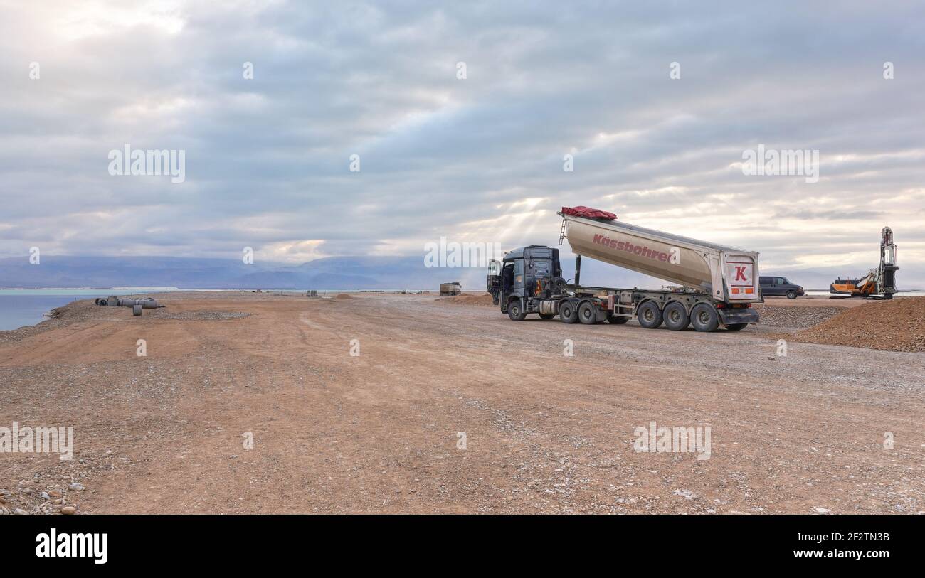 Ein Bokek, Israel - 22 de enero de 2020: Construcción de camiones en la costa del Mar muerto durante la mañana nublado preparando terreno llano para más hoteles en resorts Foto de stock