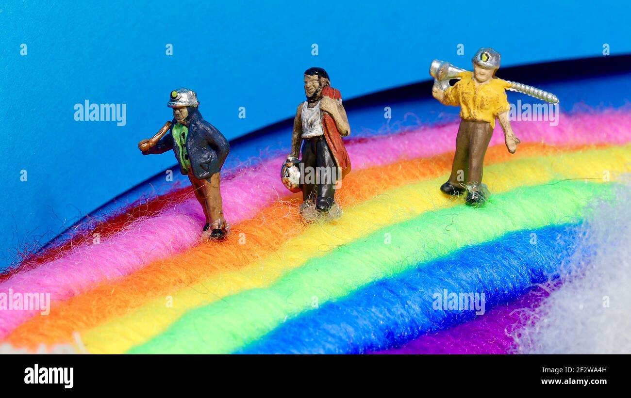 Tres mini mineros modelo esperando encontrar una olla de oro al final del arco iris. Foto de stock
